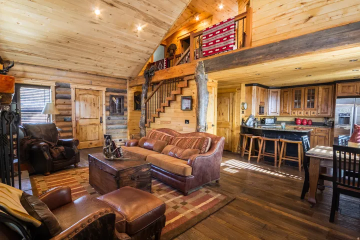 Living room with stairs, dark wood finished floors, high vaulted ceiling, wooden ceiling, and rustic walls