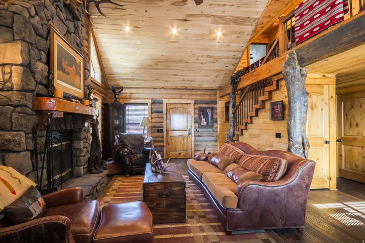 Living room featuring high vaulted ceiling, wooden ceiling, hardwood / wood-style floors, a stone fireplace, and stairway