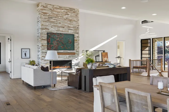 Living area with a high ceiling, hardwood / wood-style flooring, and a stone fireplace