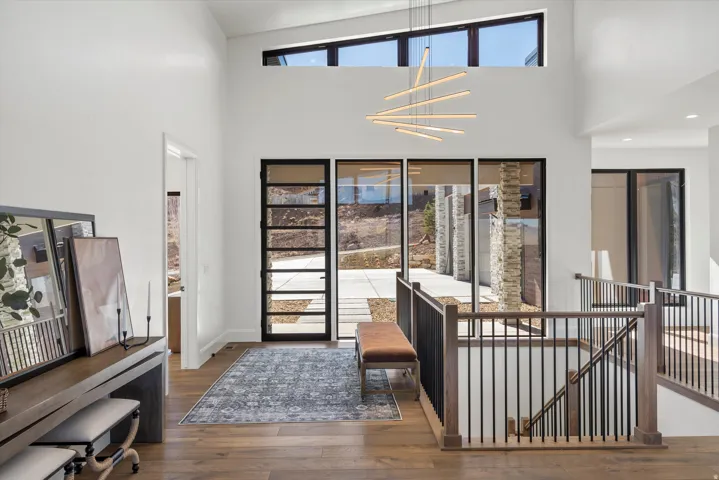 Living room with dark wood-type flooring, hanging lights, and a high ceiling