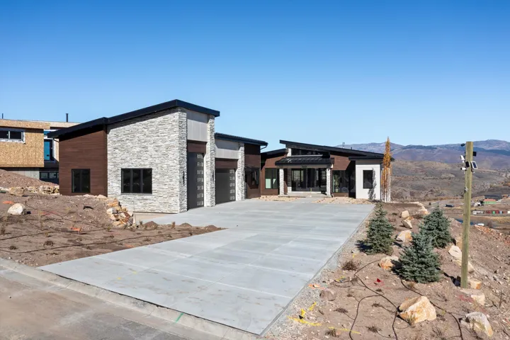 Modern home featuring stone siding, an attached garage, and concrete driveway