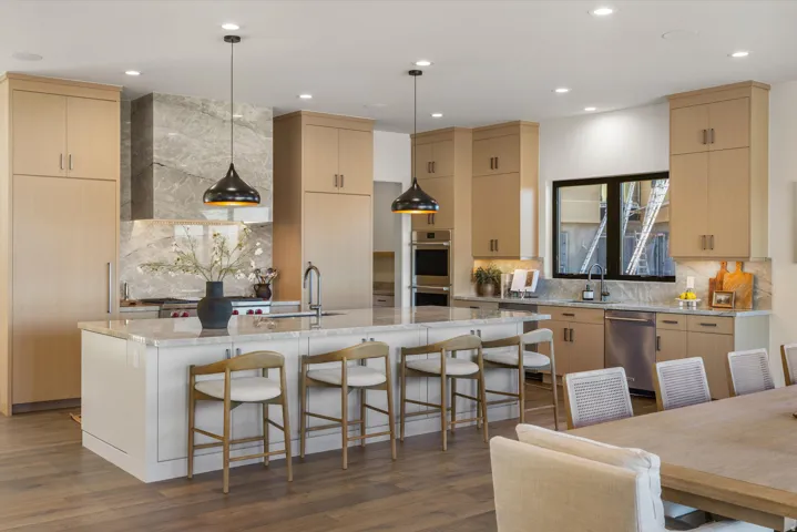 Kitchen with light wood finish cabinetry, light stone counters, a breakfast bar, and a large island
