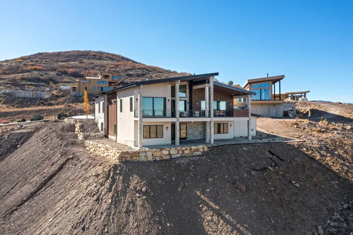 Rear view of house featuring a mountain view, a balcony, and a patio area