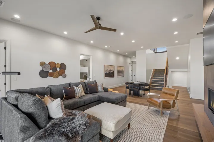 Living room featuring wood finished floors, recessed lighting, ceiling fan, a tile fireplace, and a high ceiling