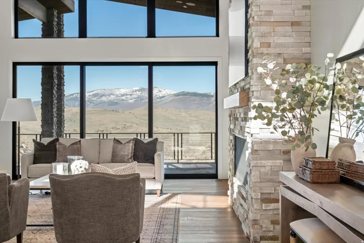 Living area featuring a mountain view, wood finished floors, a fireplace, a high ceiling, and healthy amount of natural light