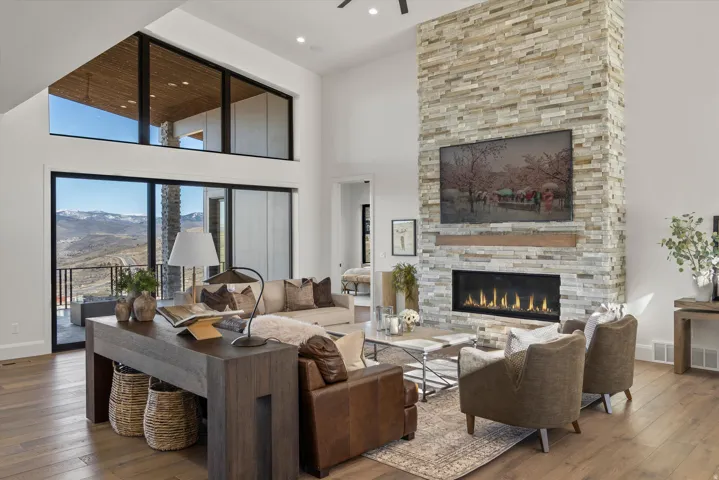 Living area featuring wood-type flooring, a mountain view, a high ceiling, a stone fireplace, and recessed lighting