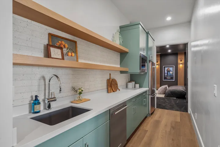Kitchen featuring green cabinets, open shelves, dark wood-type flooring, backsplash, and stainless steel appliances