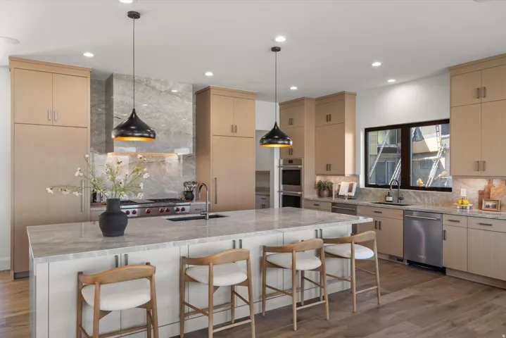 Kitchen with light stone countertops, light wood finish cabinetry, tasteful backsplash, and dark wood-type flooring