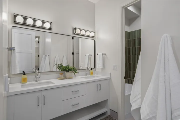 Bathroom featuring double vanity and shower / bath combination with curtain