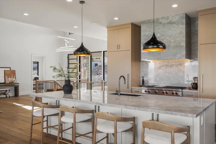 Kitchen with decorative backsplash, dark wood-type flooring, a kitchen bar, light stone counters, and light wood finish cabinetry
