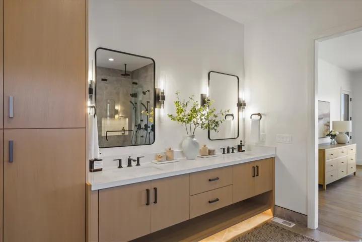 Full bathroom featuring double vanity, a stall shower, and connected bathroom