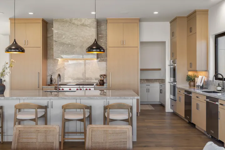 Kitchen with backsplash, light wood finish cabinetry, and light stone countertops