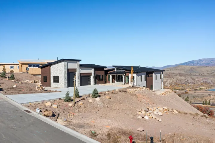 View of front of home with stone siding, driveway, a mountain view, a garage, and a patio