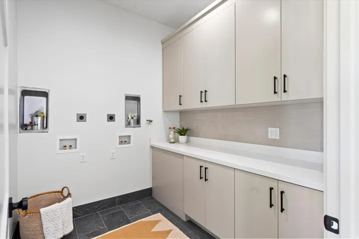 Laundry room with cabinet space, stone tile floors, hookup for an electric dryer, and hookup for a washing machine