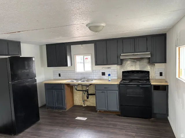 Kitchen with light countertops, black appliances, backsplash, dark wood-style floors, and gray cabinetry