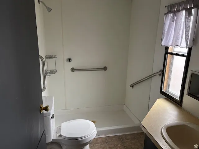 Full bathroom with vanity, walk in shower, and dark tile patterned floors