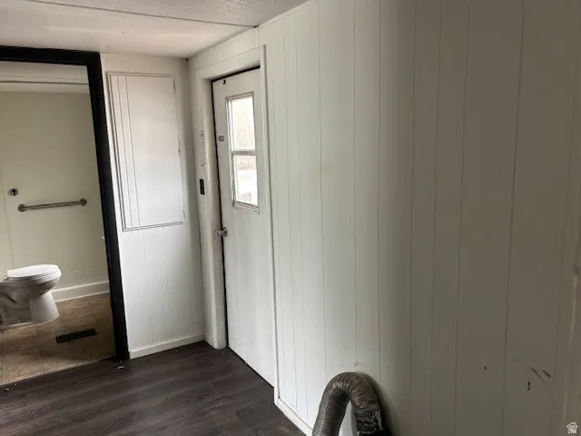 Foyer entrance with dark wood-style floors and wood walls