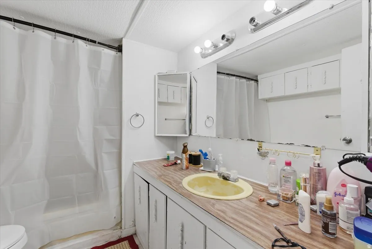 Full bath featuring vanity, curtained shower, and a textured ceiling