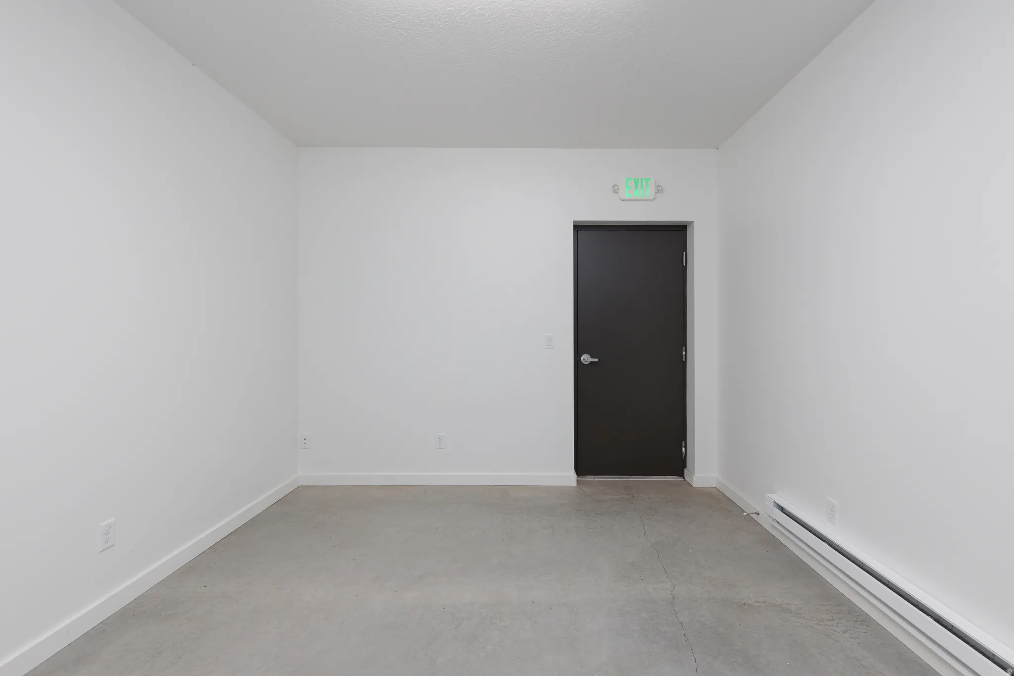 Spare room with a baseboard heating unit and finished concrete floors