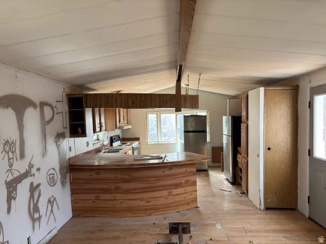 Kitchen featuring a peninsula, freestanding refrigerator, light wood-type flooring, and white range with electric stovetop
