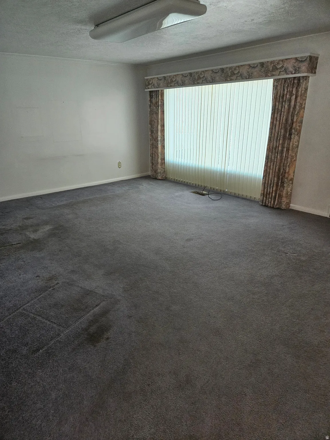 Empty room with dark carpet and a textured ceiling