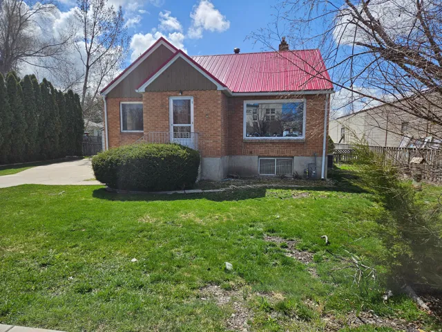 View of front of home featuring a metal roof, brick siding, and a chimney
