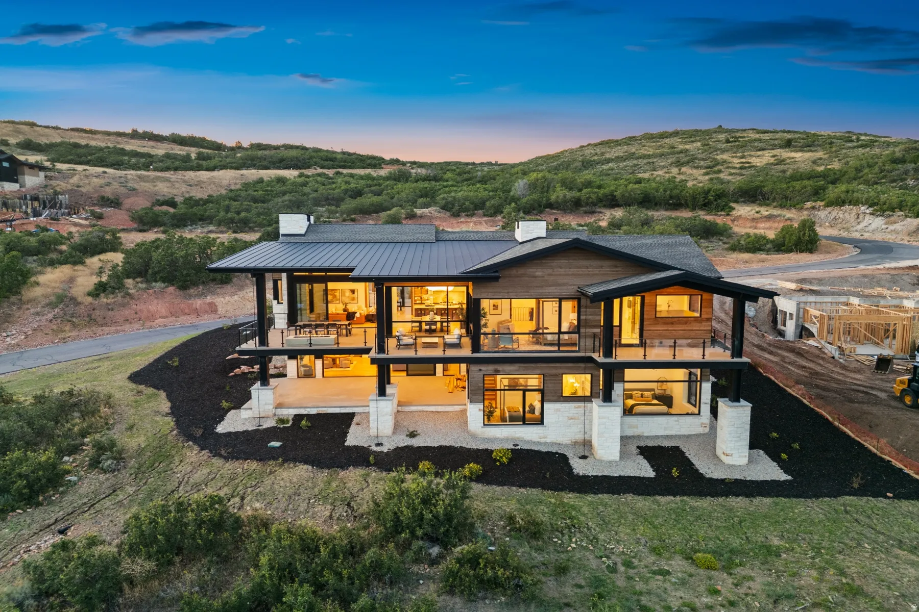 Modern architectural design with a dark metal roof, wood siding, and stone accents