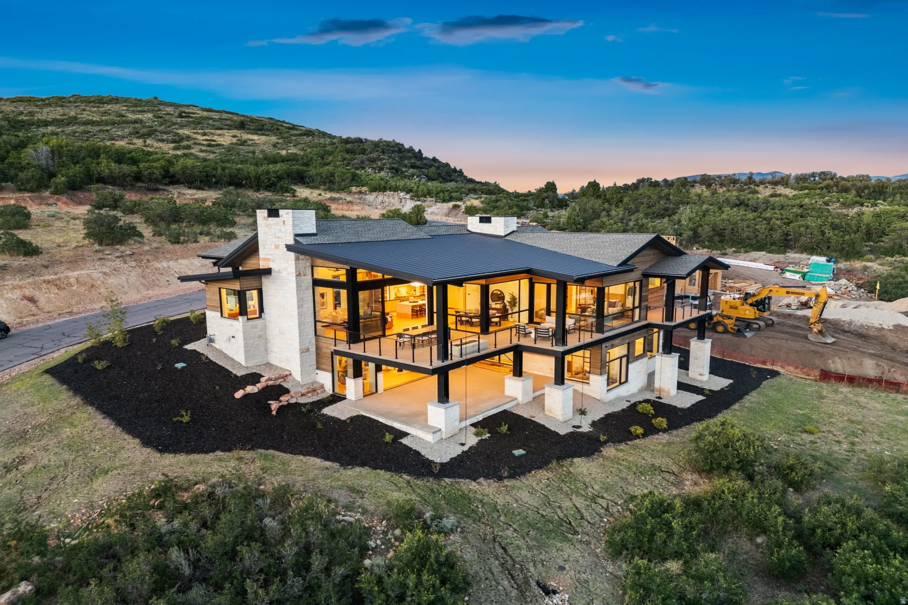 Modern architectural design with extensive glass window walls, multiple balconies and patios, natural stone and wood-finish exterior accents, and a dark-toned roof
