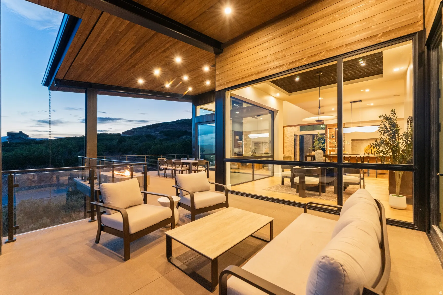 Expansive covered outdoor patio featuring a wood-finish ceiling, recessed lighting, and a glass safety railing