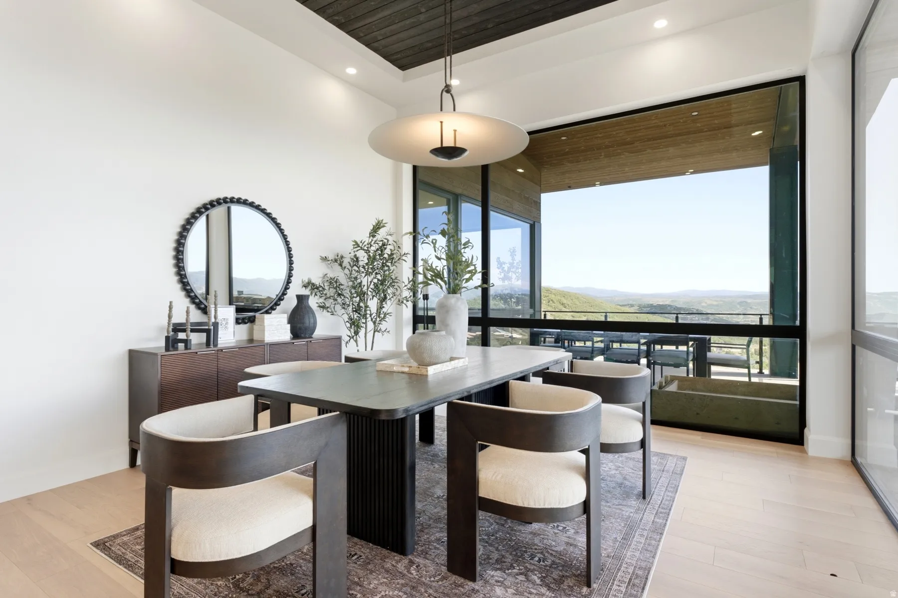 Dining area with expansive window wall, light wood-finish flooring, recessed lighting, and a dark wood ceiling detail