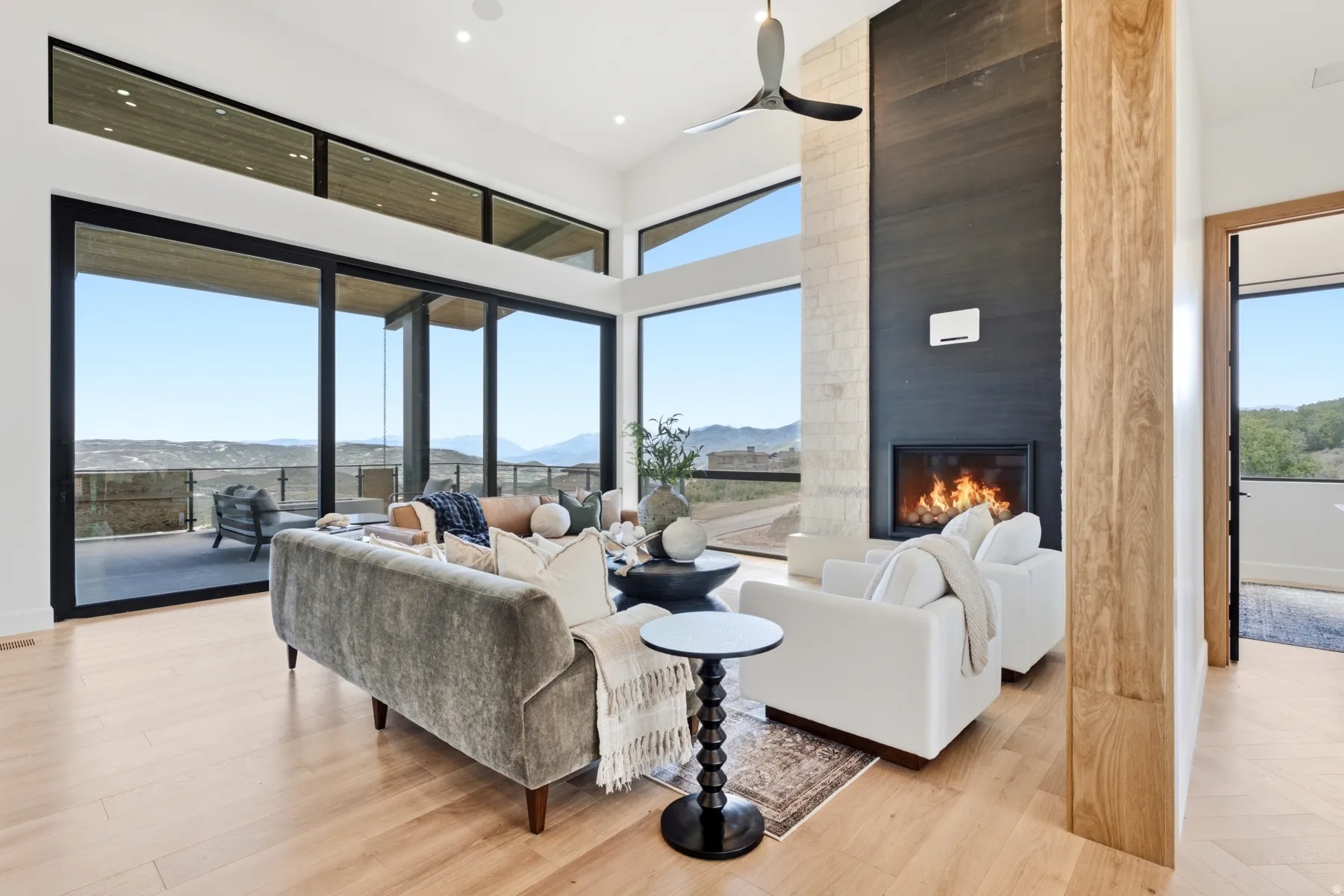 Contemporary living space featuring expansive glass doors, clerestory windows, and light wood-finish flooring