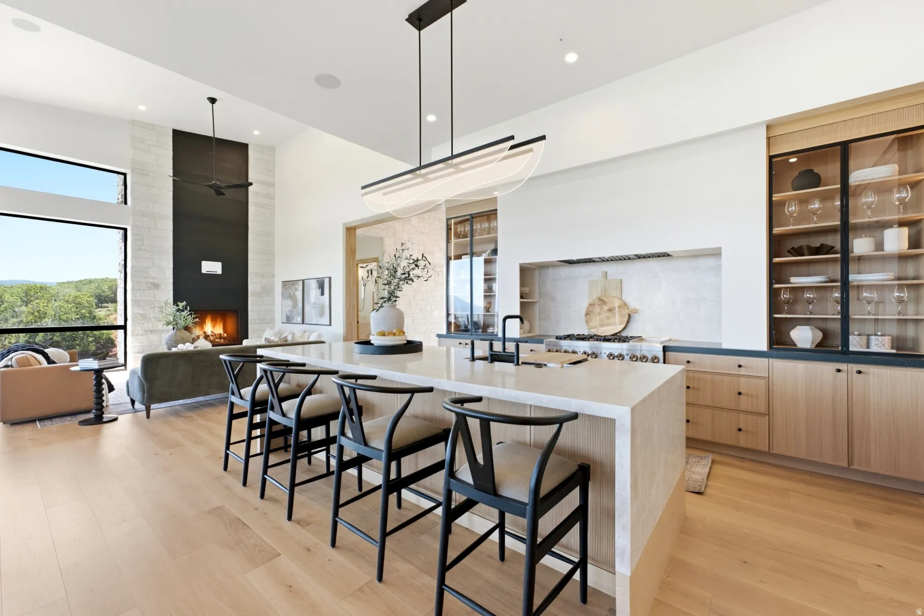 Open-concept kitchen featuring an expansive island with seating, a professional-grade range, and built-in display cabinetry