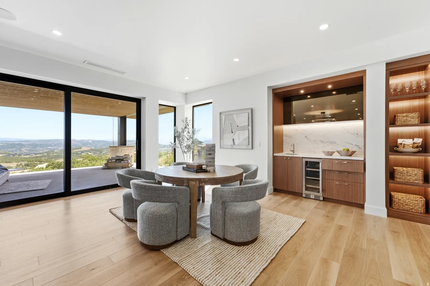 Spacious room featuring wood-finish flooring, a built-in wet bar with a beverage refrigerator and marble backsplash, and integrated shelving with accent lighting