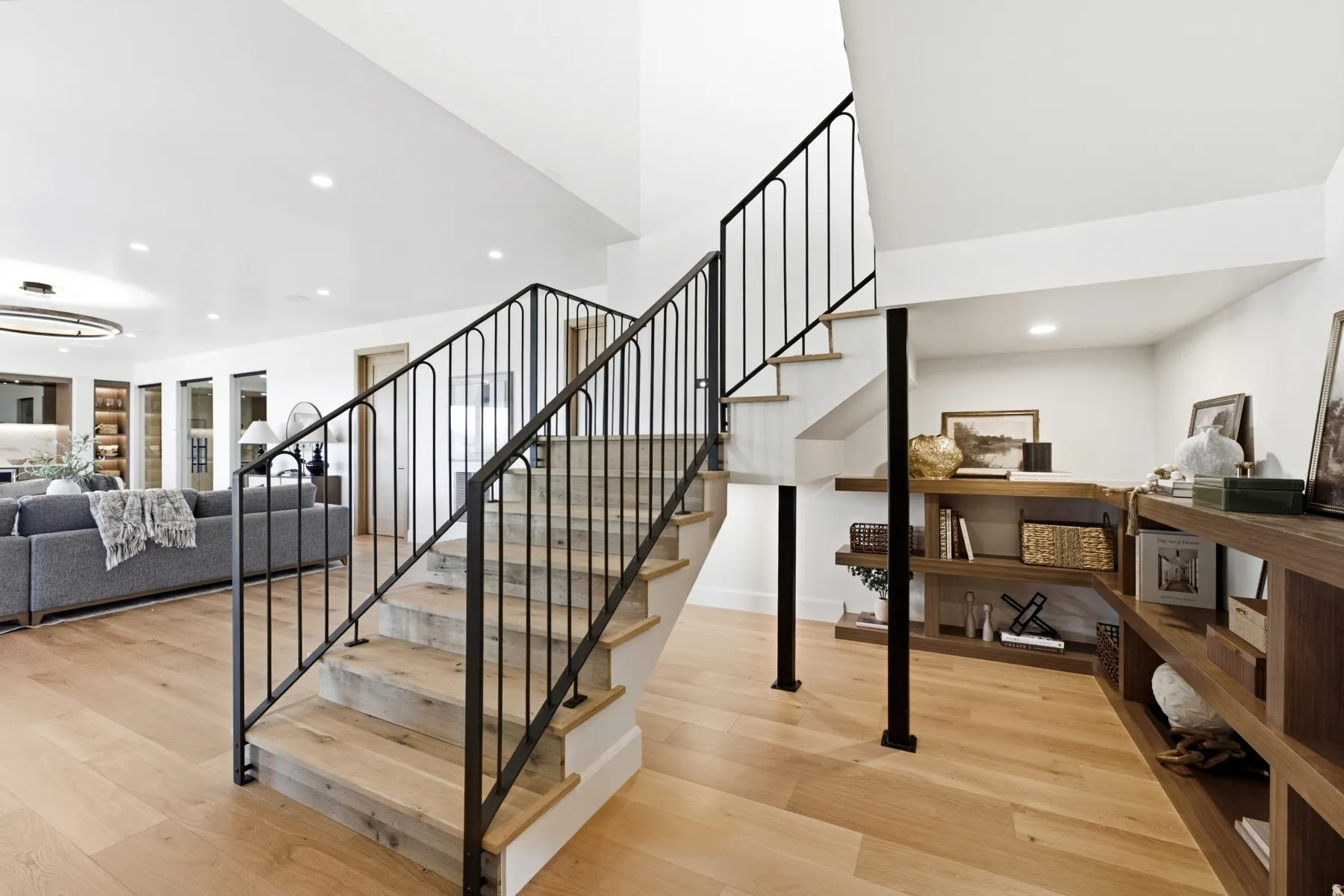 Hardwood flooring throughout the main level featuring a staircase with black metal balusters and wood treads