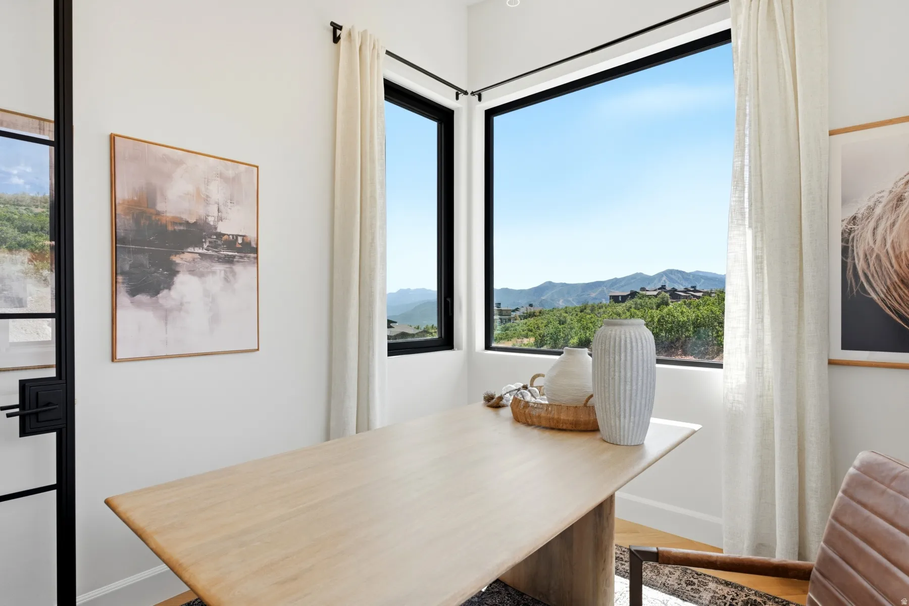 Corner window framing a mountainous landscape with a bright blue sky