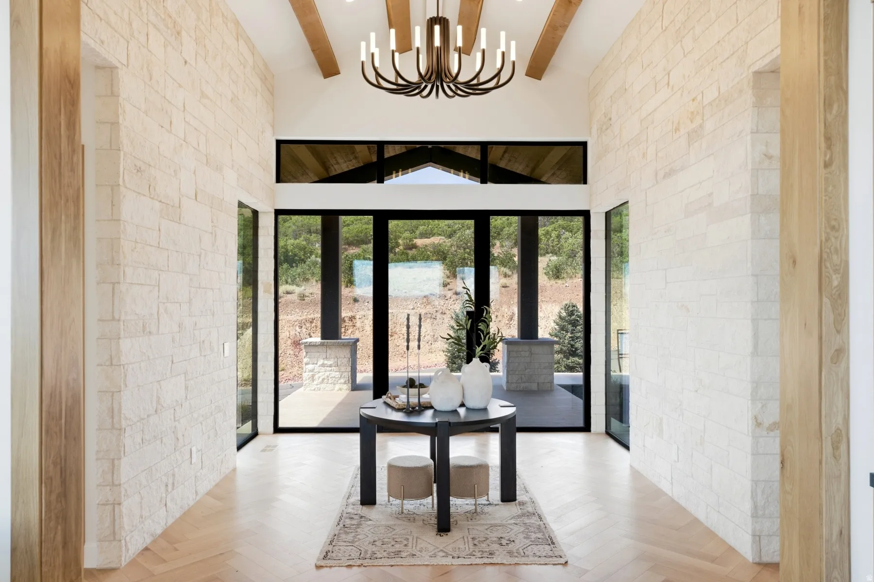 Entryway featuring light-toned stacked stone walls, wood-finish herringbone flooring, and a vaulted ceiling with exposed wood beams