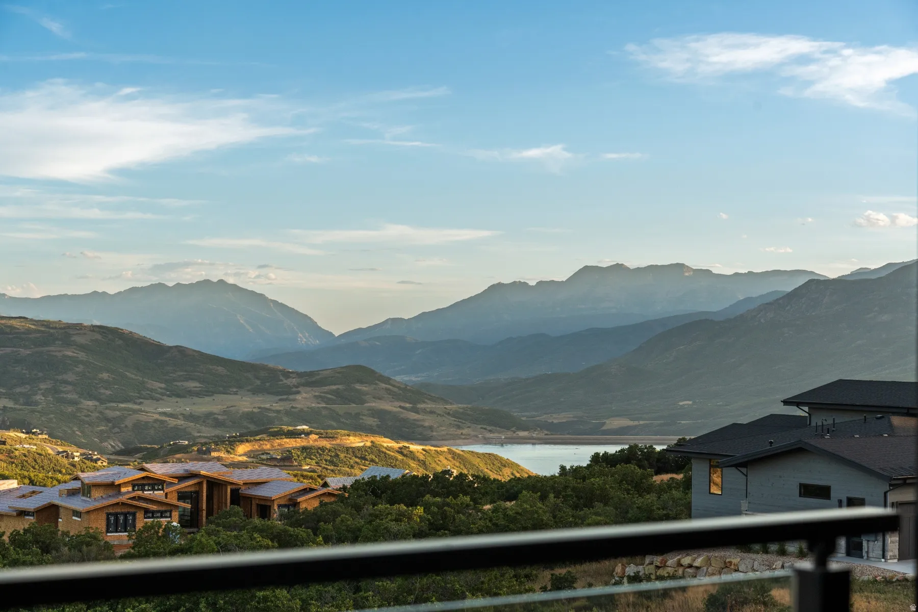 Balcony with glass railing overlooking mountainous scenery and a body of water
