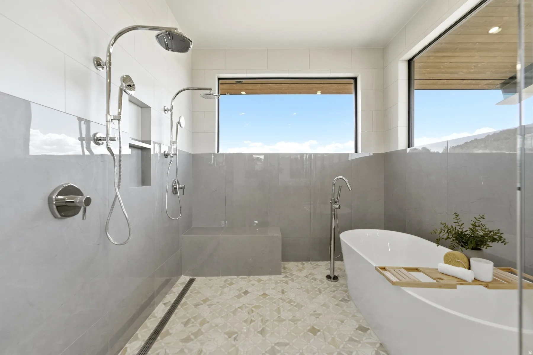 Expansive walk-in shower with dual shower heads, integrated bench, and mosaic tile flooring