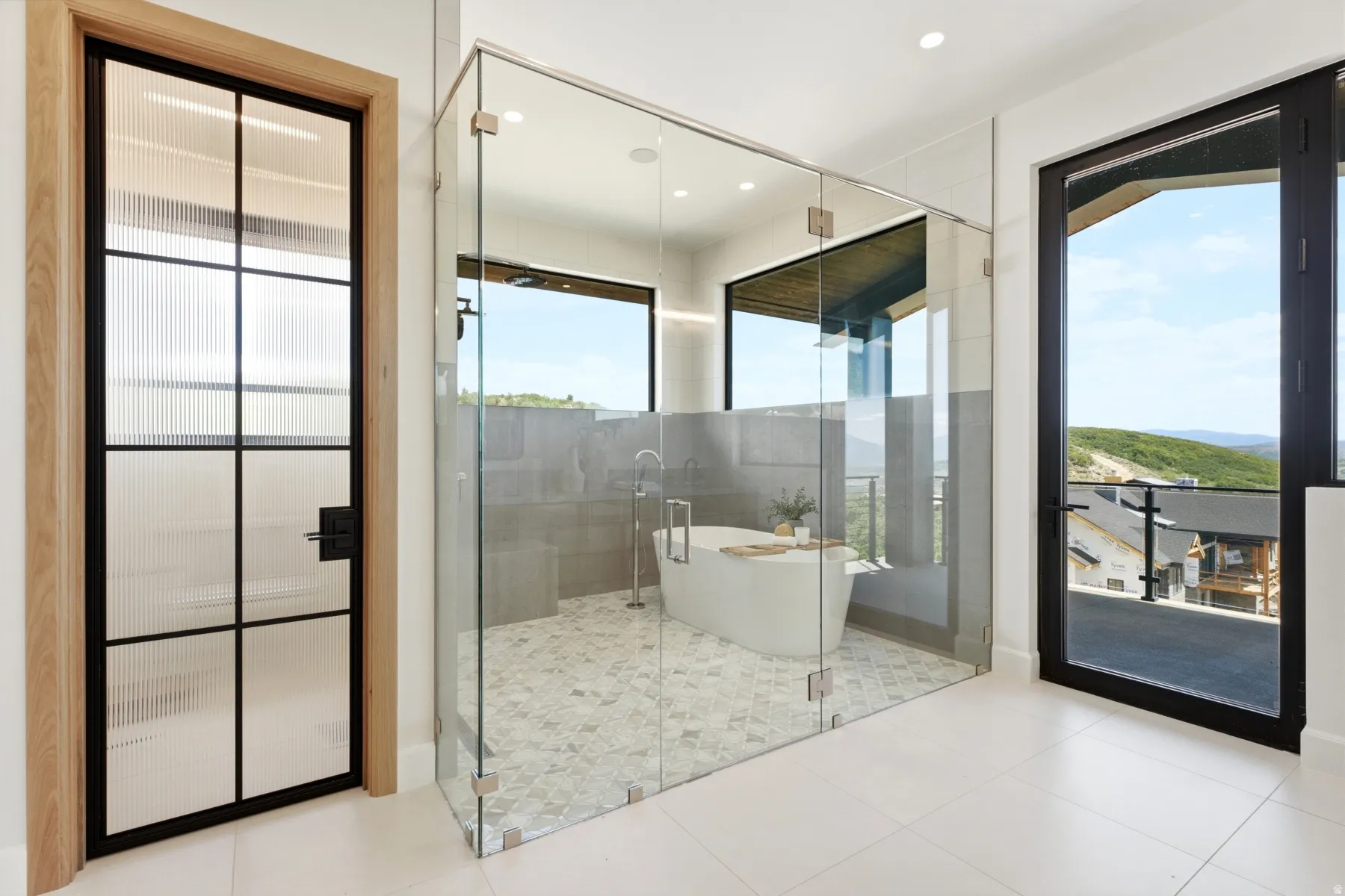 Spacious bathroom featuring a freestanding tub, glass-enclosed shower, and large format floor tiles