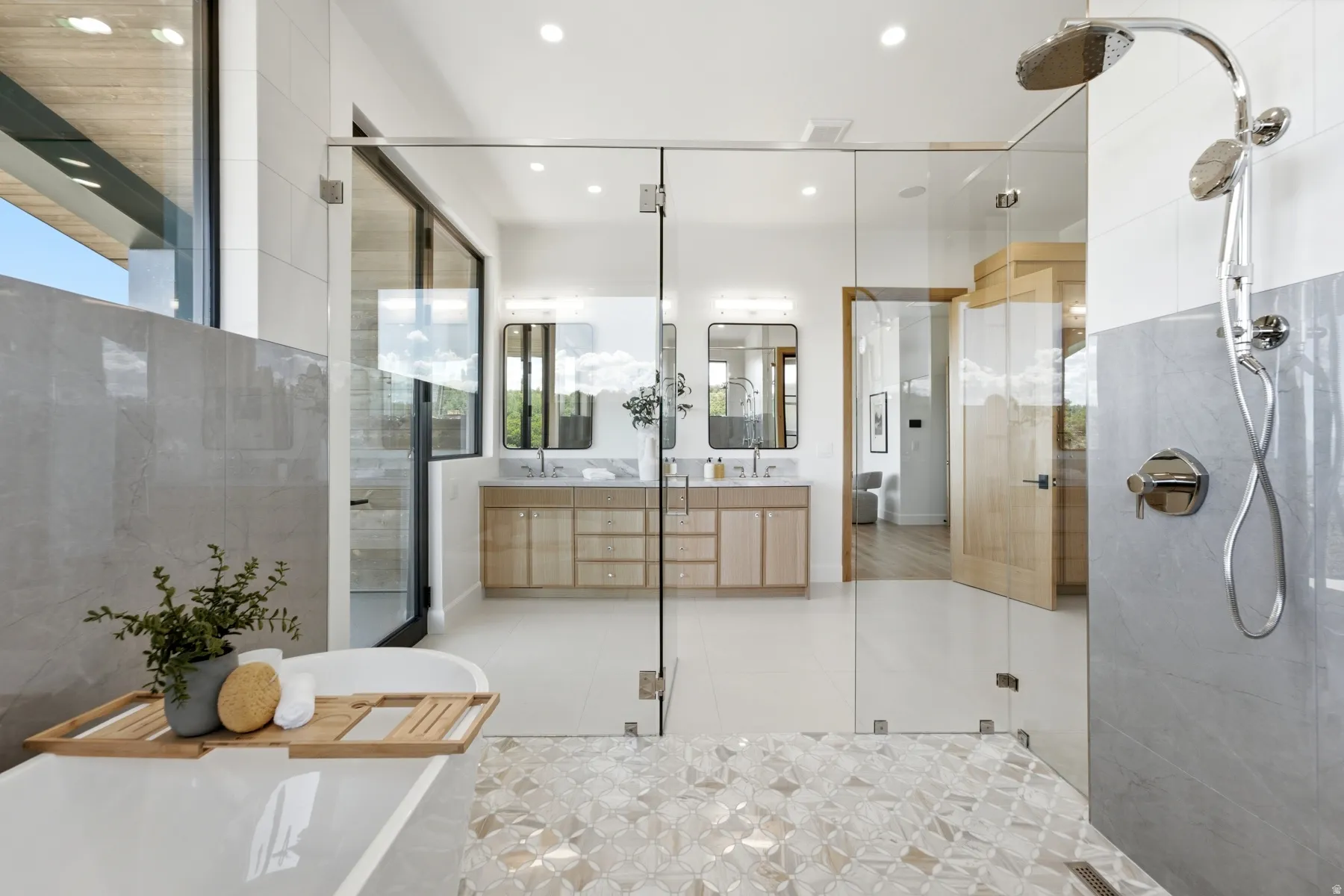 Glass-enclosed shower with multiple showerheads, dual floating vanities with undermount sinks, and a freestanding soaking tub