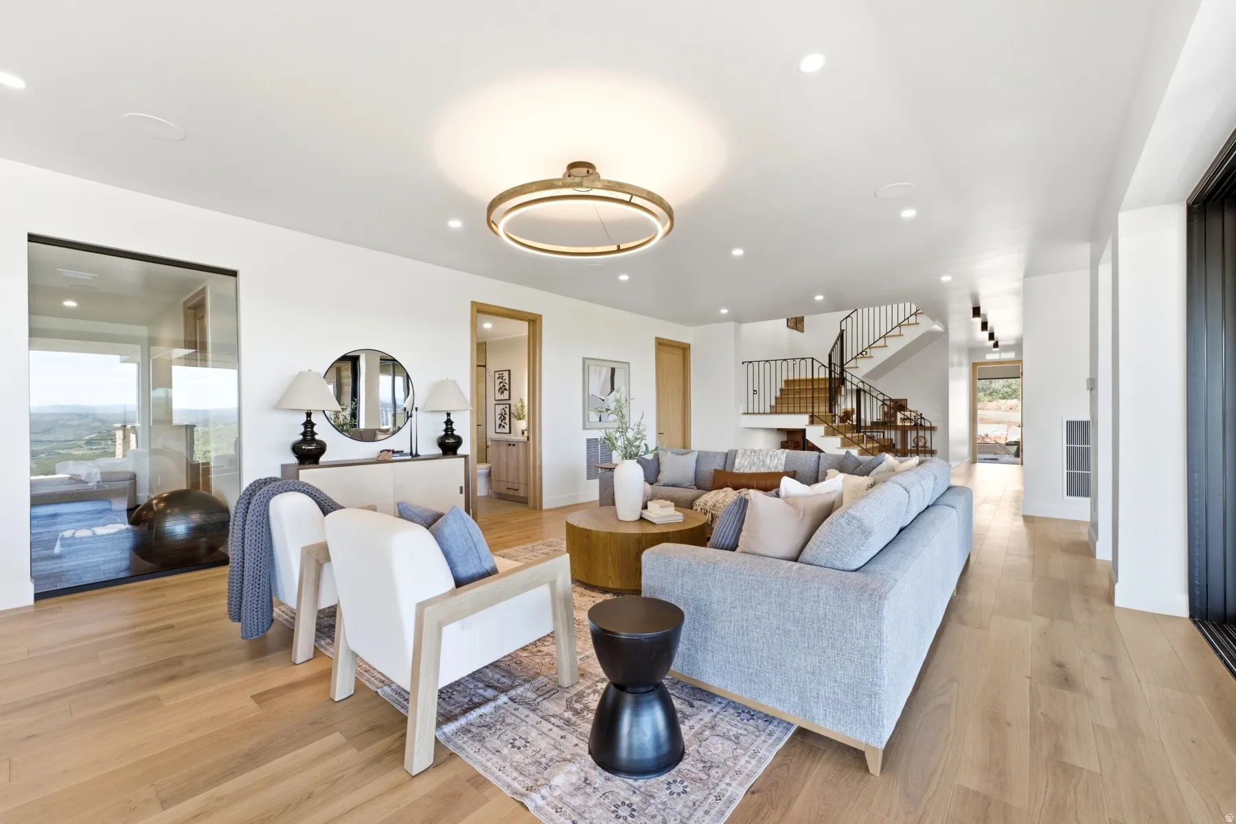 Open-concept living space featuring wood-finish flooring, recessed lighting, and a contemporary circular chandelier