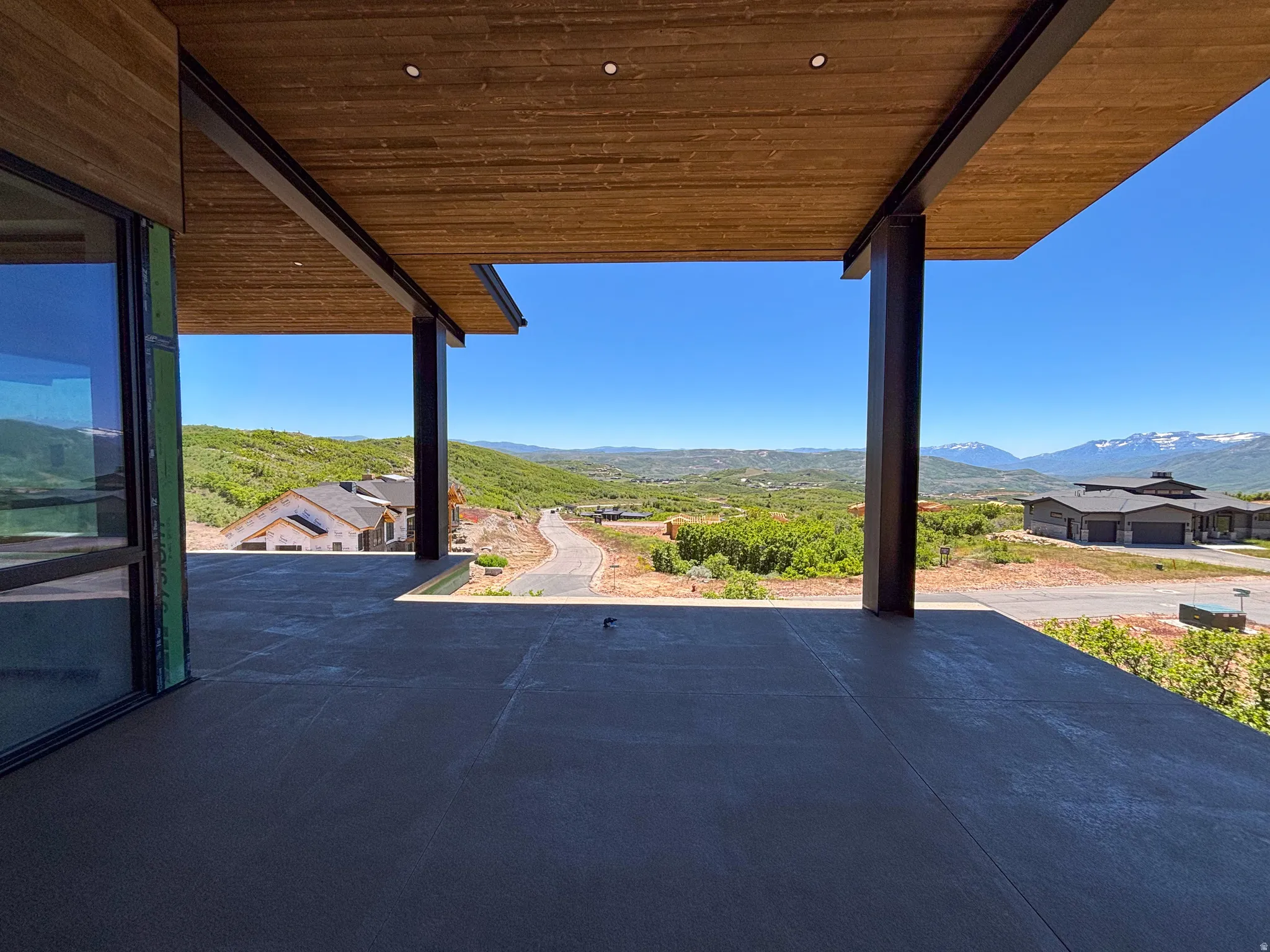 Expansive outdoor patio featuring a concrete surface, wood-finish ceiling, and recessed lighting