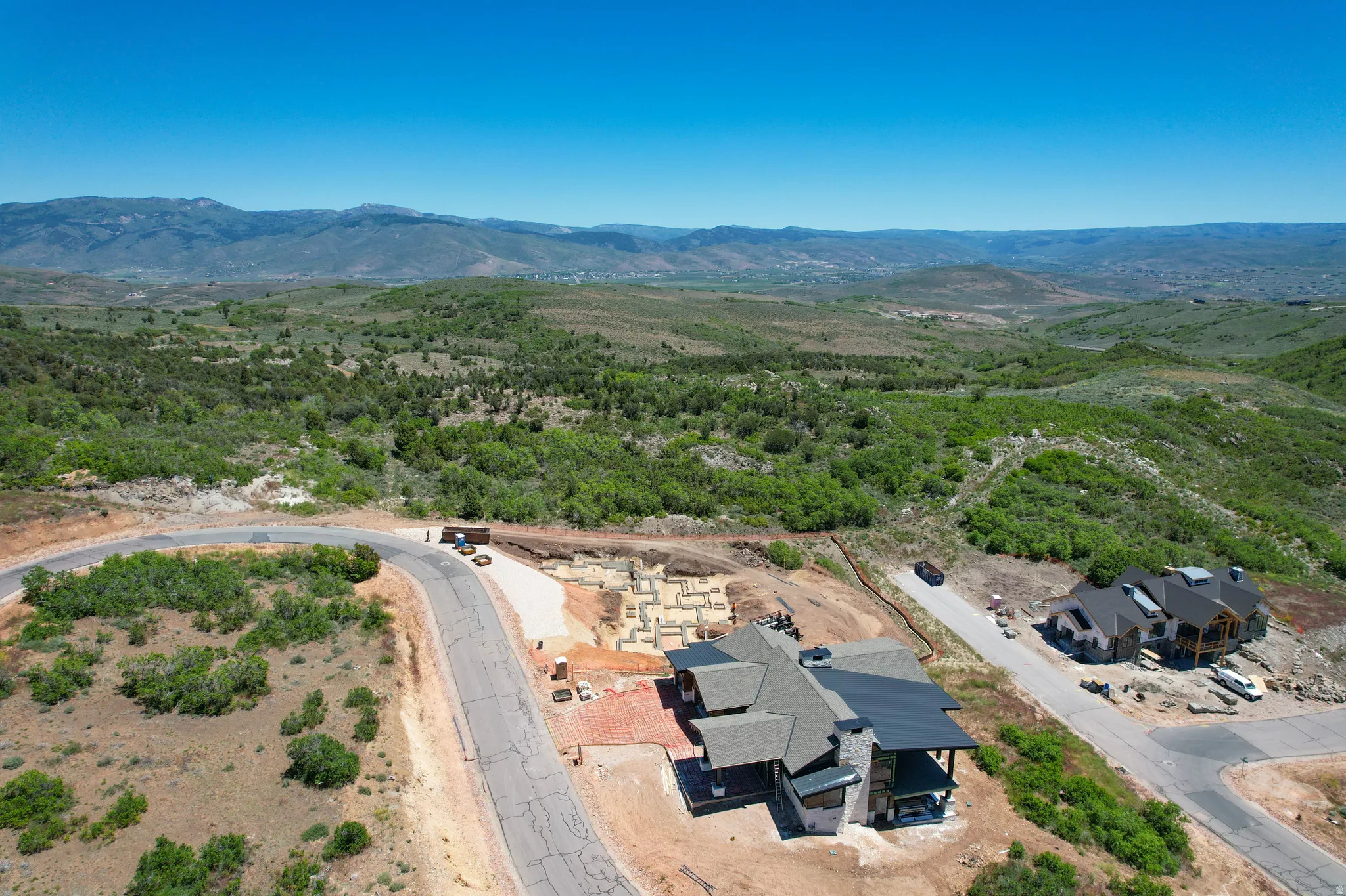 Expansive mountainous terrain with a single-family residence featuring a multi-gabled roofline and a flat roof section