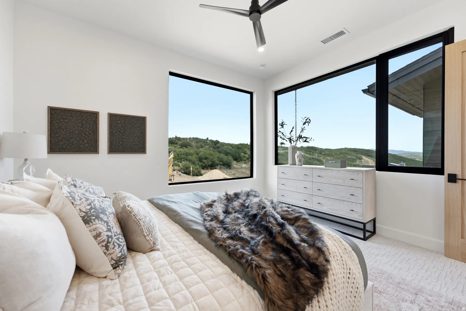 Bedroom featuring large windows with black frames, white walls, and light-toned carpeting
