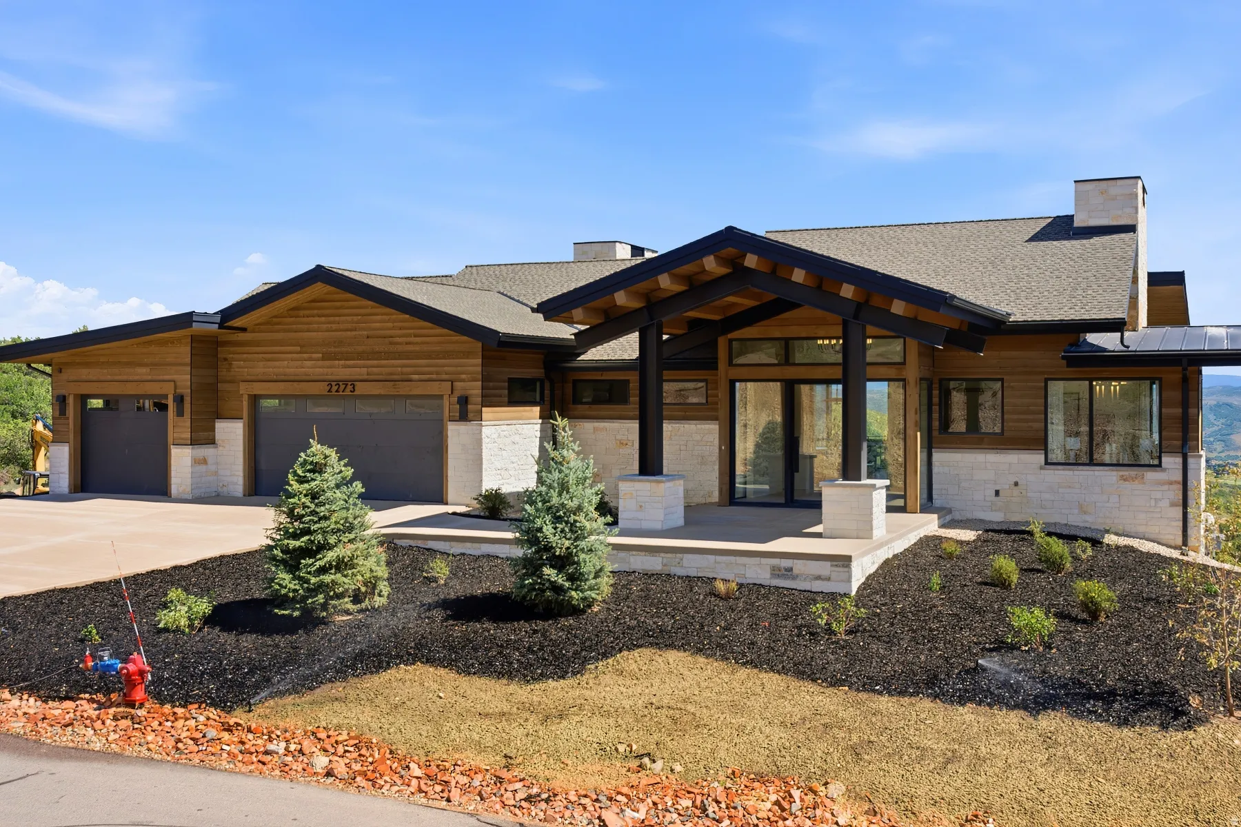 Contemporary architectural style featuring wood siding, stone accents, and a prominent covered entryway