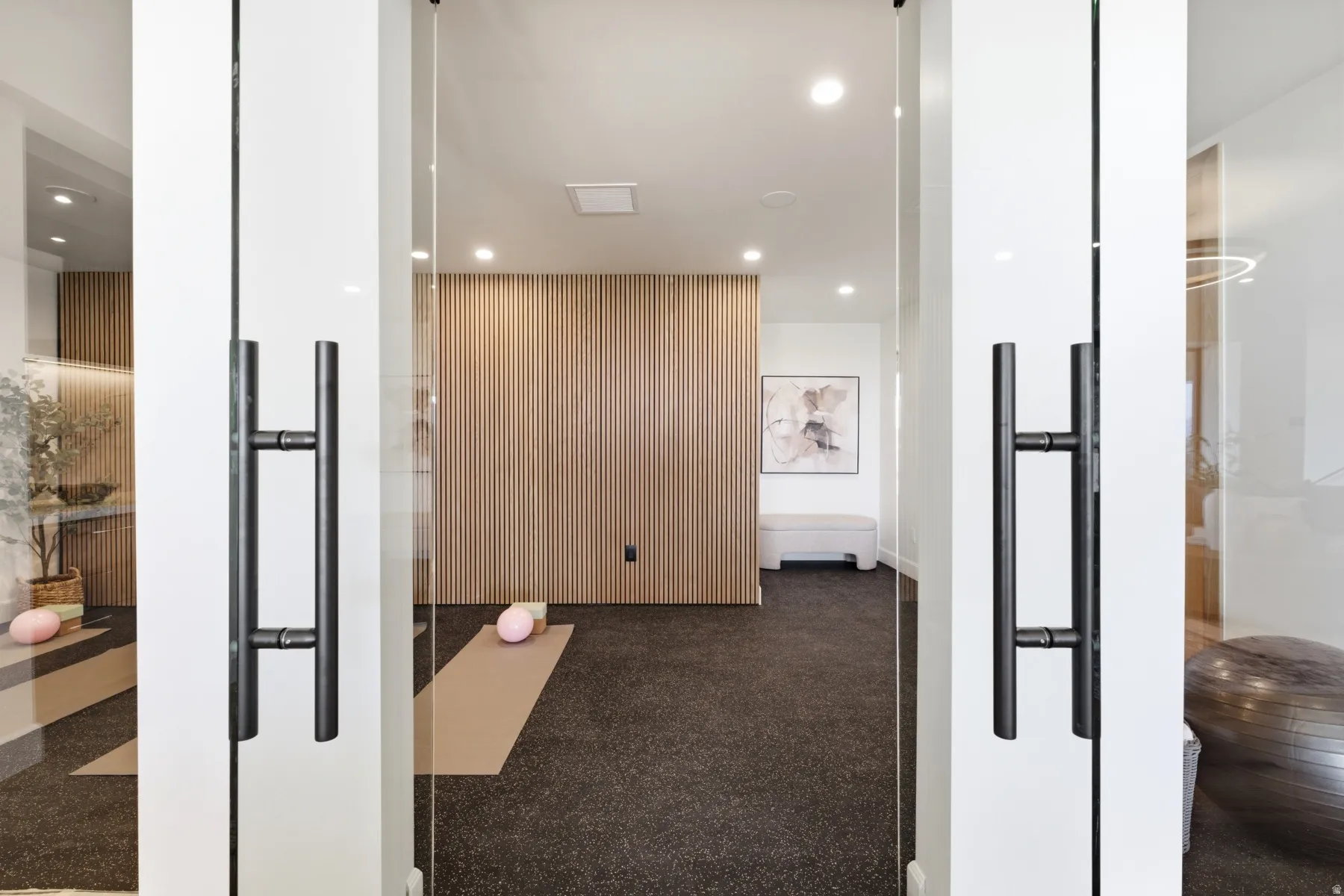 Interior space featuring full-height glass entry doors with matte black pull handles