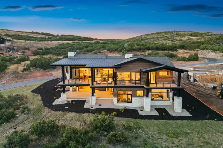 Modern architectural design with a dark metal roof, wood siding, and stone accents