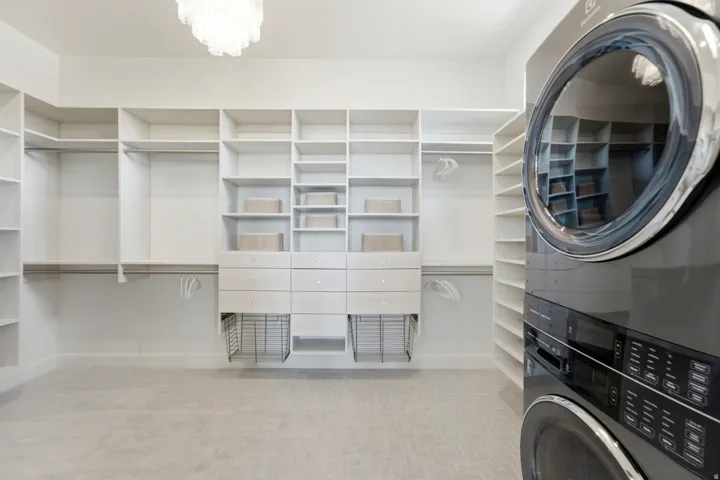 Integrated laundry appliances, extensive built-in shelving, multiple hanging rods, built-in drawers, and wire storage baskets