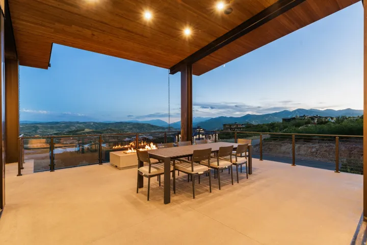 Expansive outdoor deck with a wood-paneled ceiling, integrated lighting, and a built-in fire feature