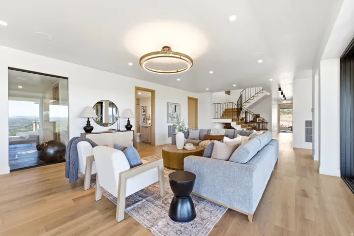 Open-concept living space featuring wood-finish flooring, recessed lighting, and a contemporary circular chandelier